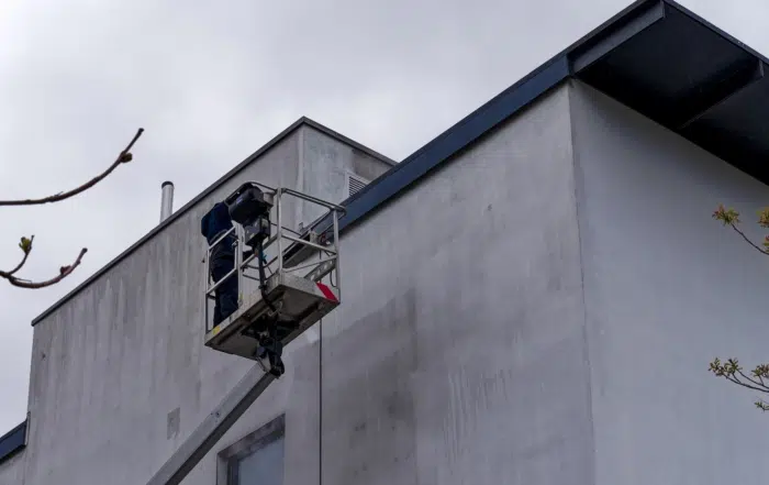 Man in lift cleaning building exterior in Farnham.
